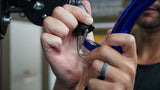 Hands clipping the blue Gronk Fitness curl bar's carabiner to a cable machine pulley