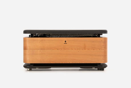 Front view of a warm golden-wood storage bench with the padded lid raised and resistance bands visible inside