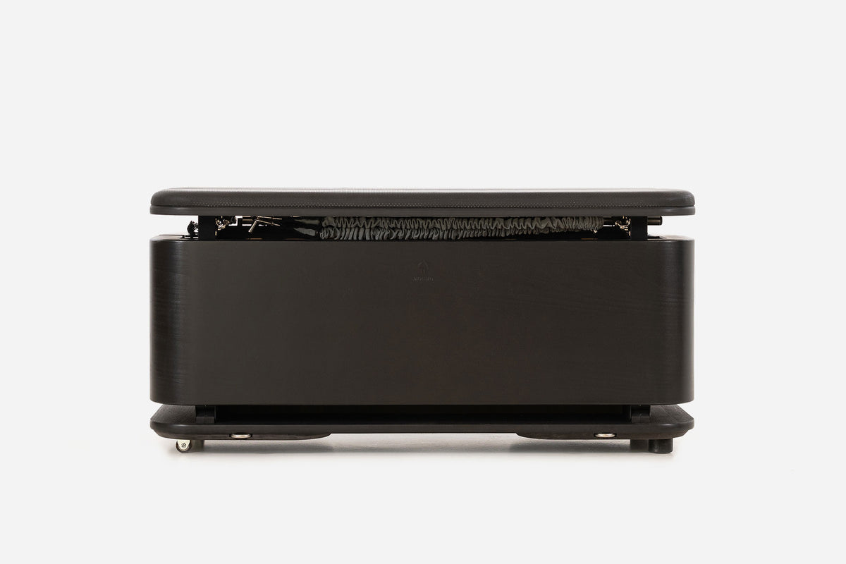 Front view of a black storage bench with the padded lid raised and resistance bands visible inside